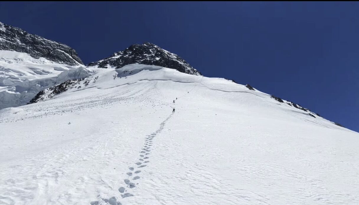 Climbers on a snow slope, a broke snow slab in front of them.