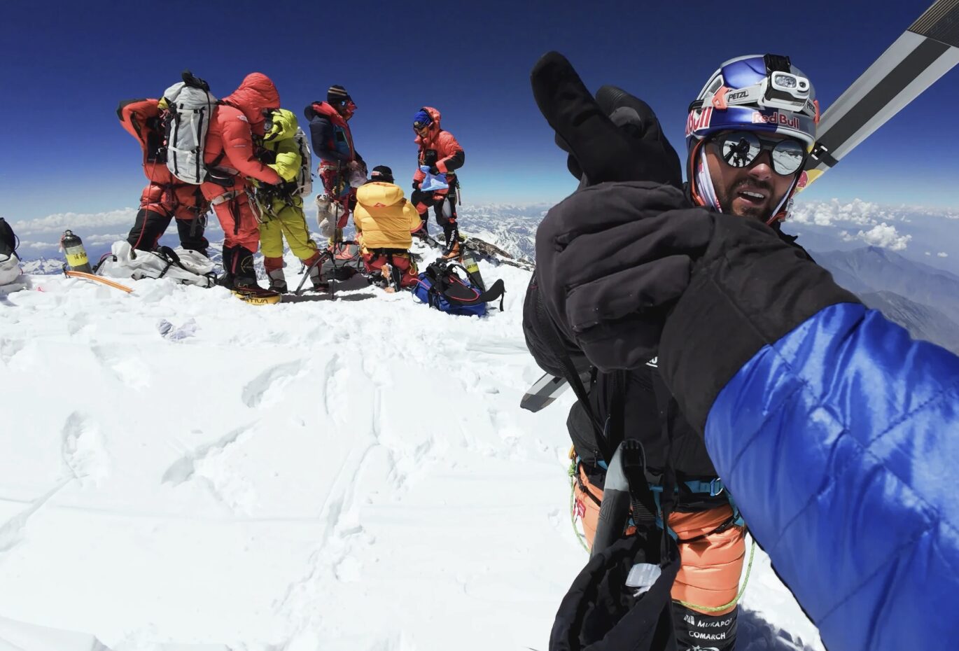 Bargiel shakes hands with the photographer on the summit of Nanga parbat, a group of skiers in background.