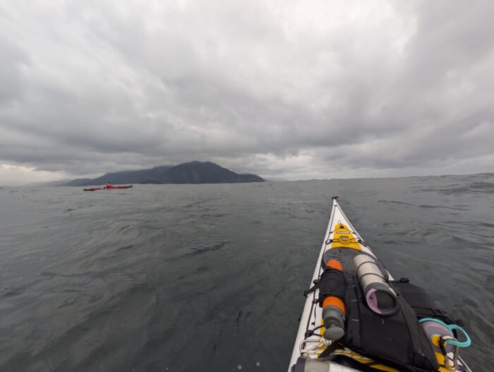 Dark skies above as two kayakers paddle the coast of Moresby Island, British Columbia