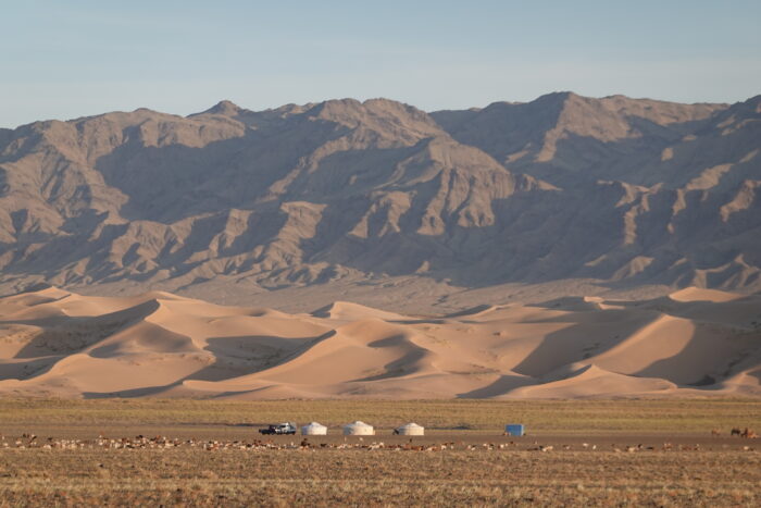 Distant yurts set against sand dunes and mountains in Mongolia