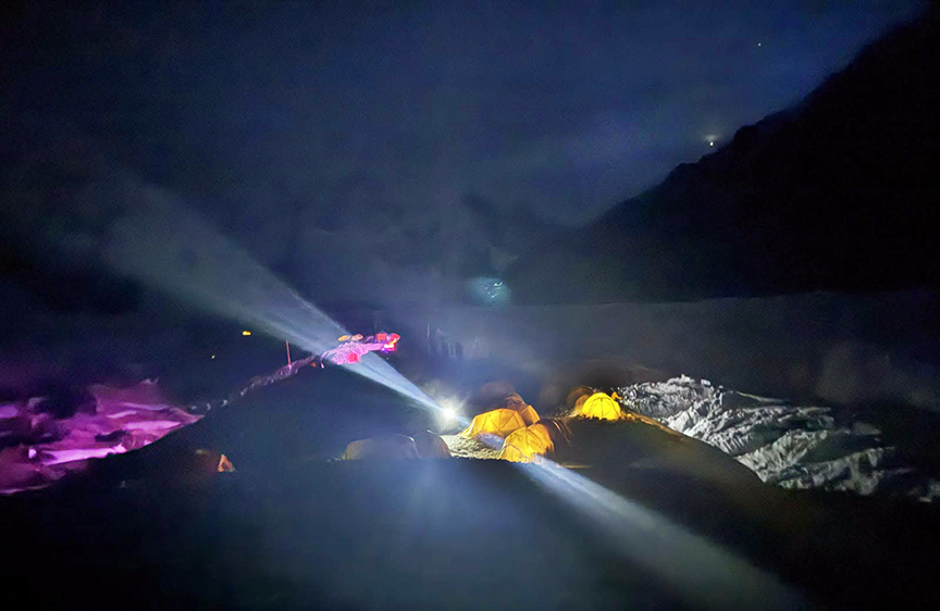 Tents lit up in different colors on a glacier at night.