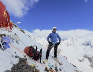 A sherpa by some tents on a steep slope on K2.