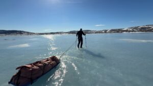 sledder hauls through meltwater atop sea ice