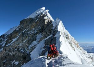 Two climbers approaching the summit of Everest in a clear day.