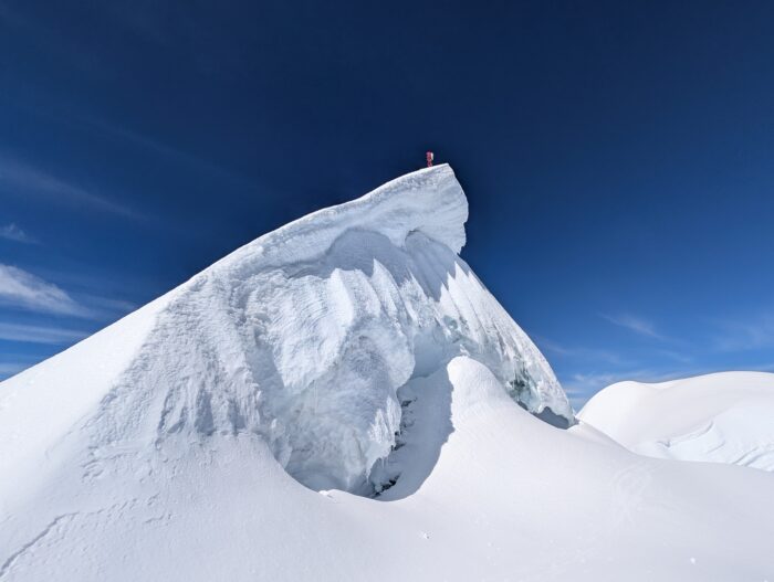 A tiny figure on a snowy summit. 