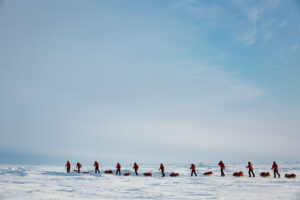 skiers pulling sleds over frozen Arctic Ocean