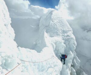 A climber traversing on gigantic snow cornices in Andes of Peru.