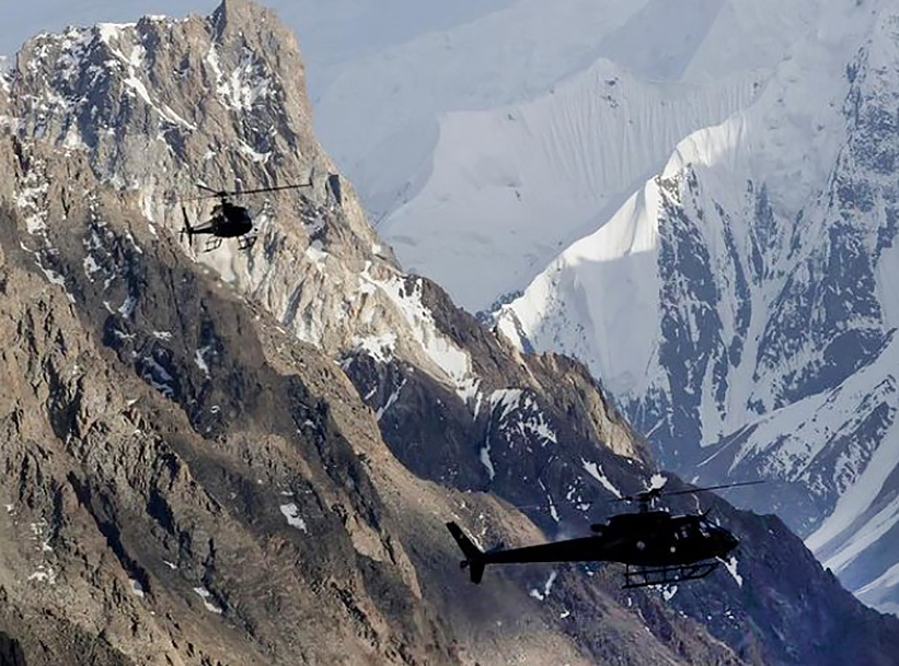 Two helicopters among big mountains.