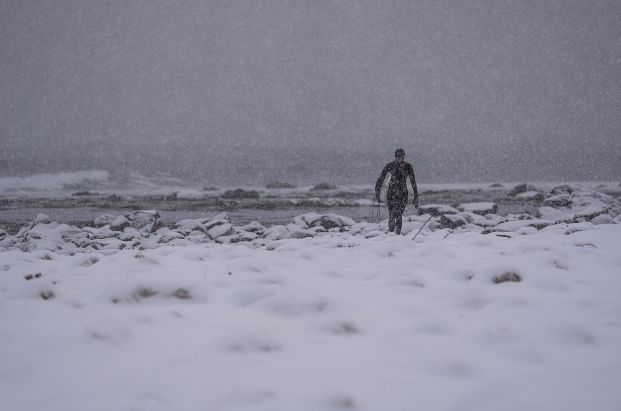 A surfer carries their surfboard across the snow in Norway. Photo: Lisa Paarvio