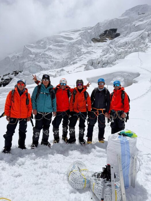 Sherpas stand in line with coils of ropes in front of them.