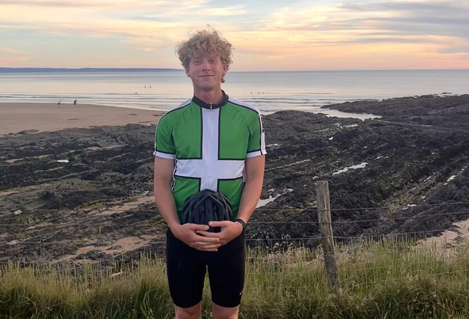 cyclist standing by coast with helmet in hand