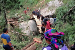 A line of Nepalese villagers cross a narrow woden bridge.
