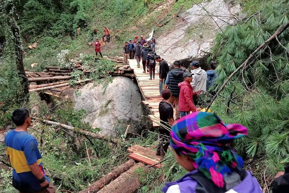 A line of Nepalese villagers cross a narrow woden bridge.